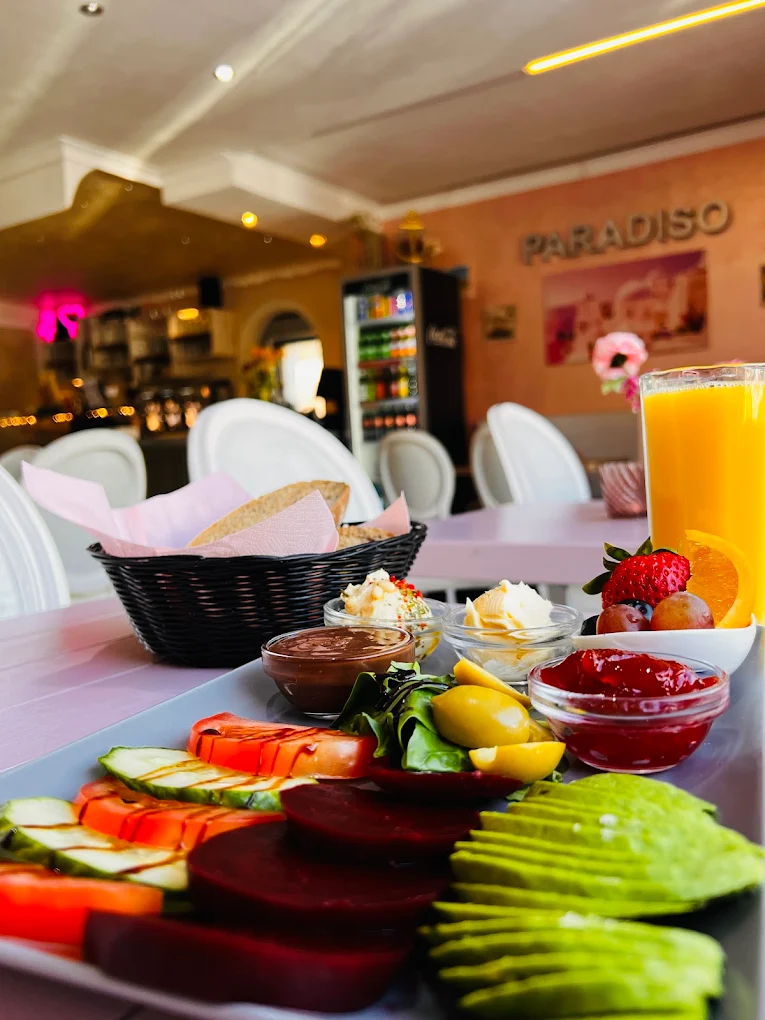 Frühstücksteller im Café Paradiso mit Brotkorb, Dips, Avocado, Beeren und frisch gepresstem Orangensaft